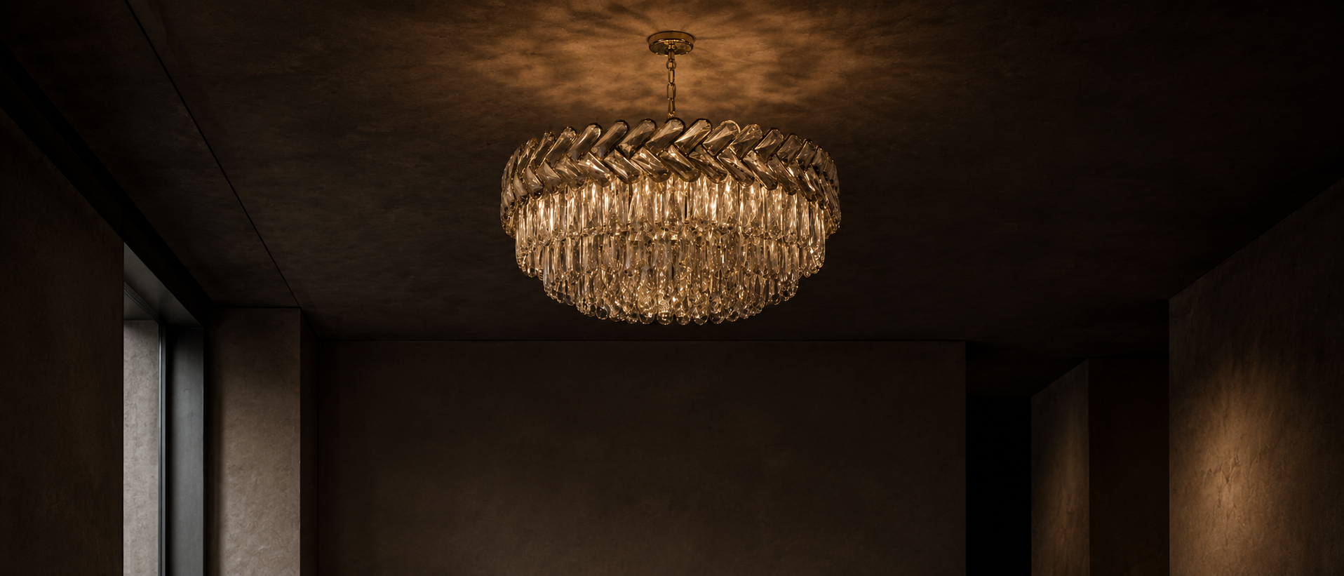 Lustre circulaire en cristal éclairant le centre d’un intérieur sombre.